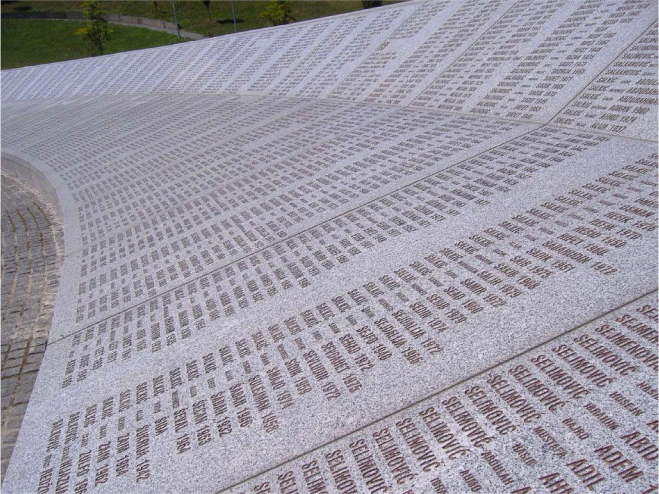 A grey stone memorial shows the names of victims of the Srebrenica genocide.